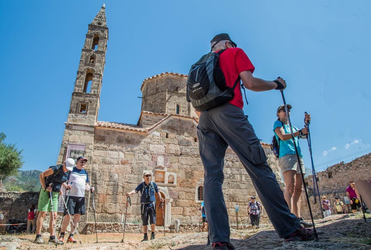 Guided hiking group exploring the traditional stone paths and historic churches of Kardamyli in Mani