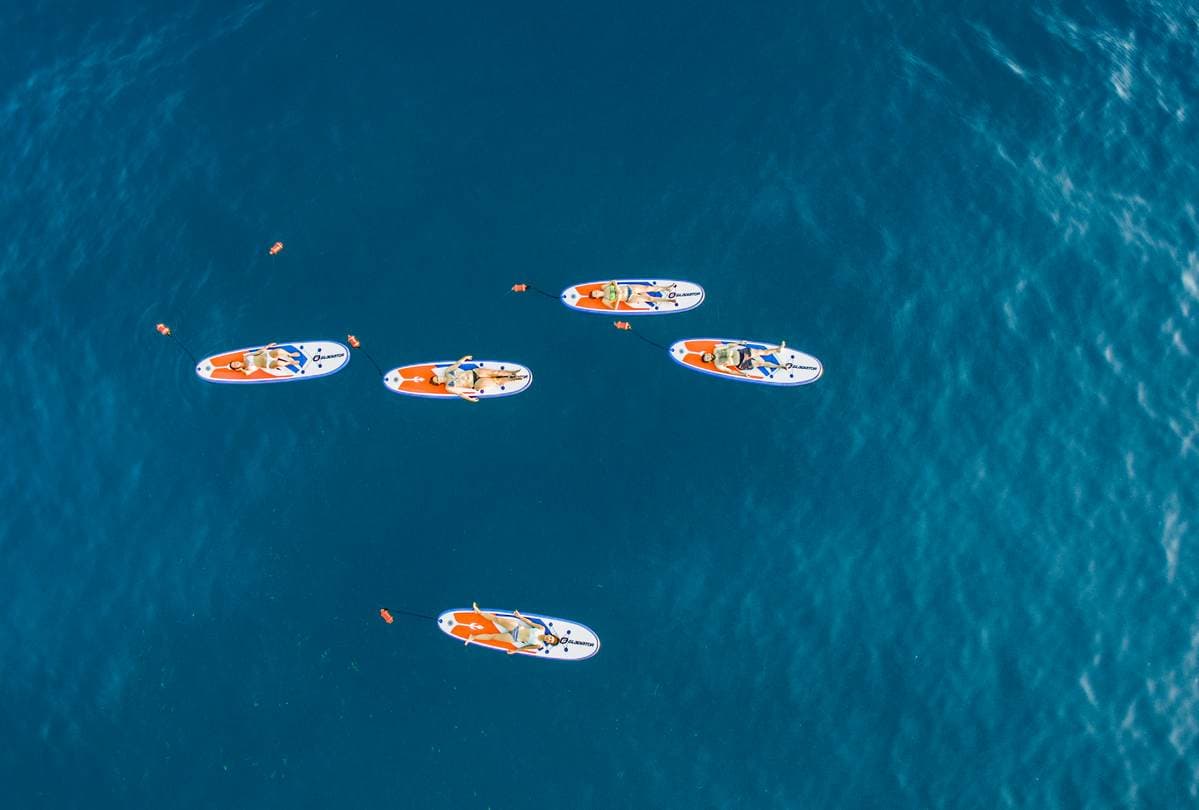 Alternative Text (Alt Text): Aerial view of guided SUP and snorkeling tour participants relaxing on paddleboards in the Messinian Gulf, Kalamata