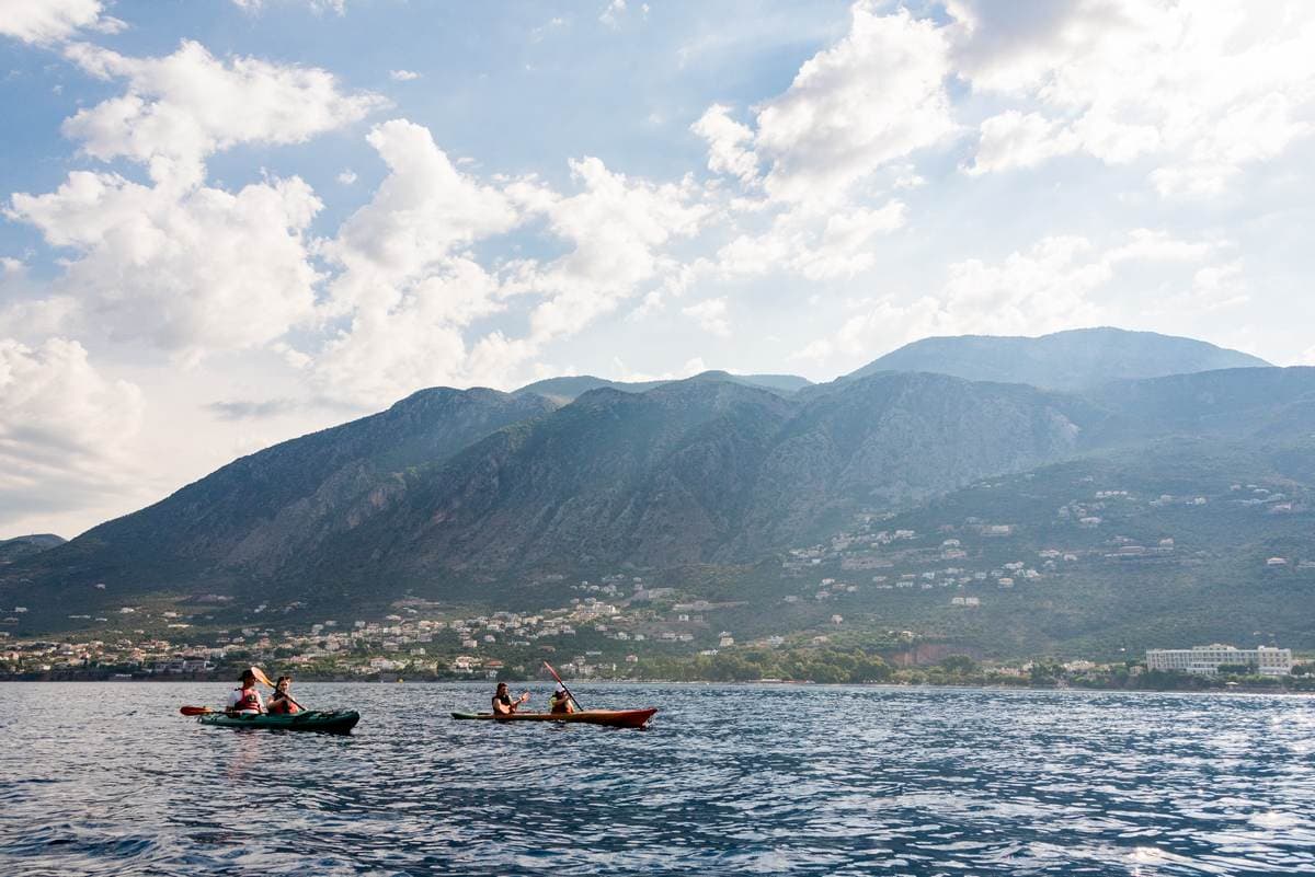 Four sea kayakers paddling with the dramatic Taygetos mountains in the background