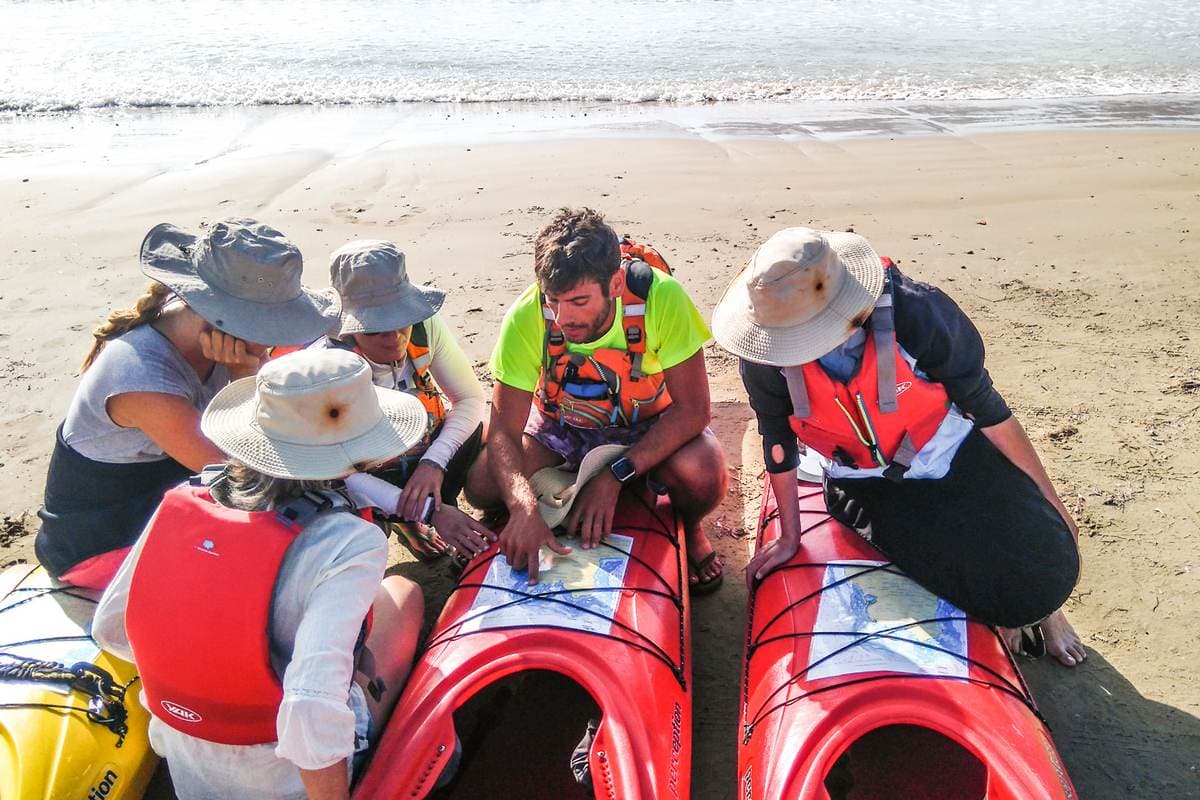 Outdoor guide showing a map to travelers on a sandy beach