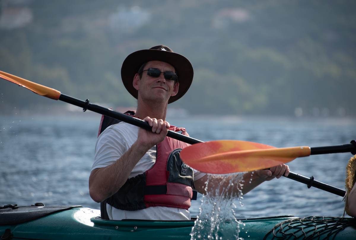 Close up of a man paddling with water splashing off the blade