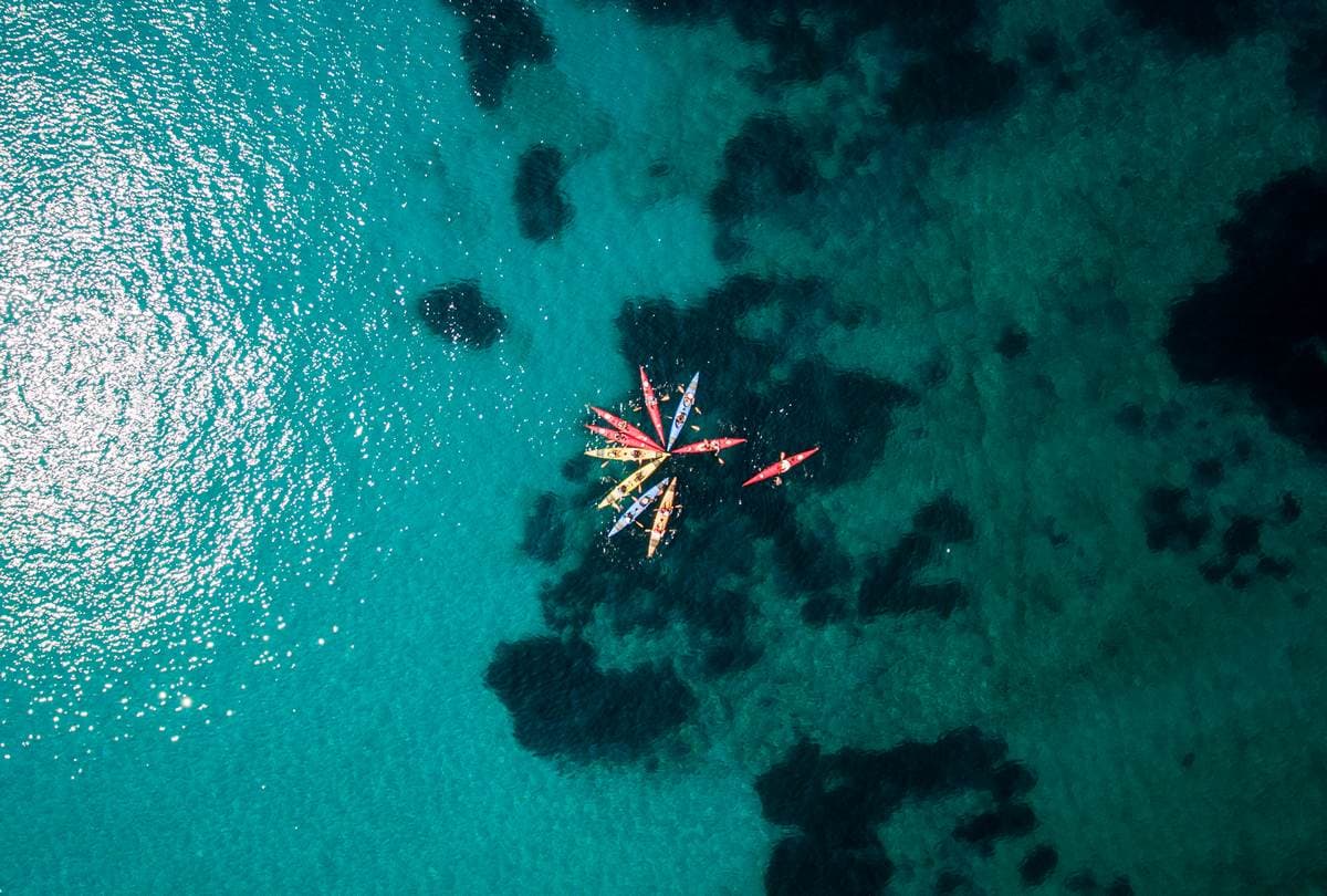 Aerial drone view of kayaks gathered in a star formation over clear reef