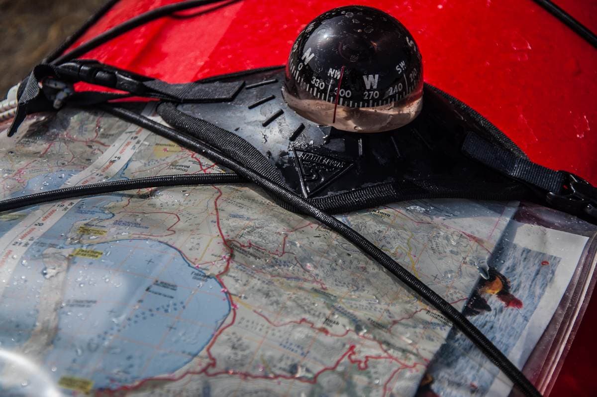 Navigation compass and topographical map on the deck of a red kayak