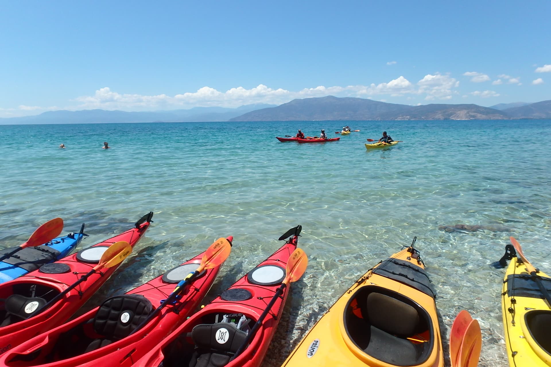 Sea kayaks lined up on a pristine beach during a family-friendly Sea Kayaking Nafplio trip