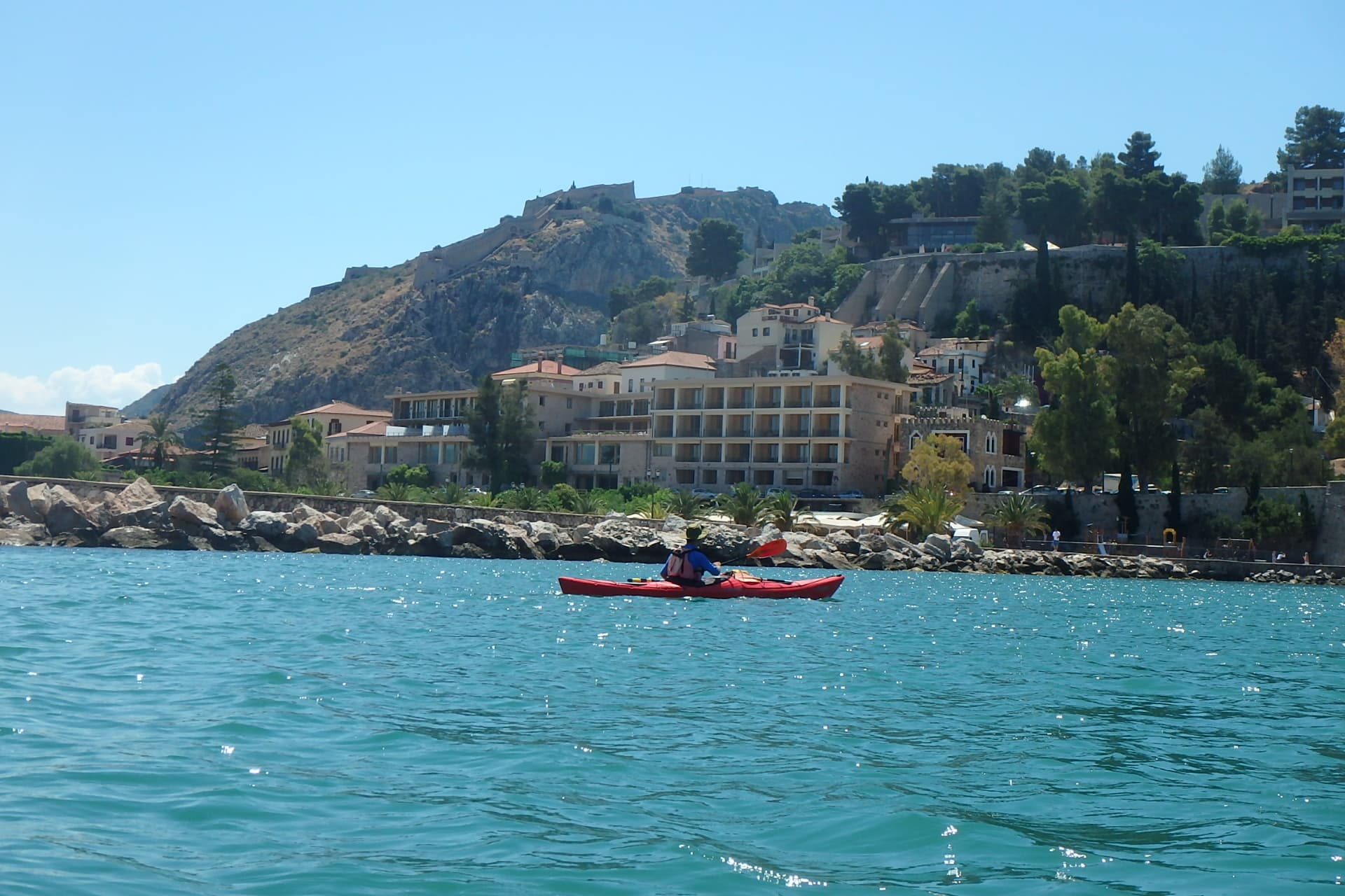 Kayaker paddling past the historic waterfront of Nafplio on a Sea Kayaking Nafplio excursion