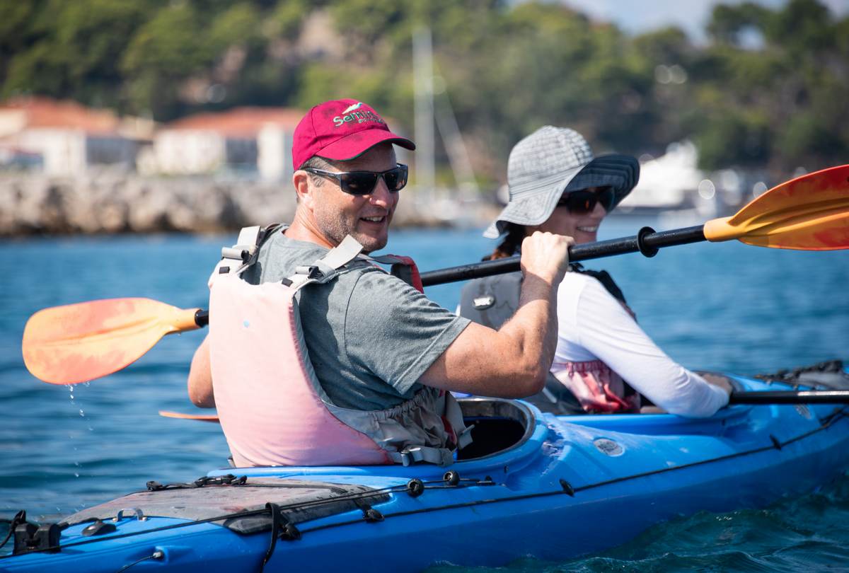Couple smiling and paddling together during sea kayaking navarino bay.