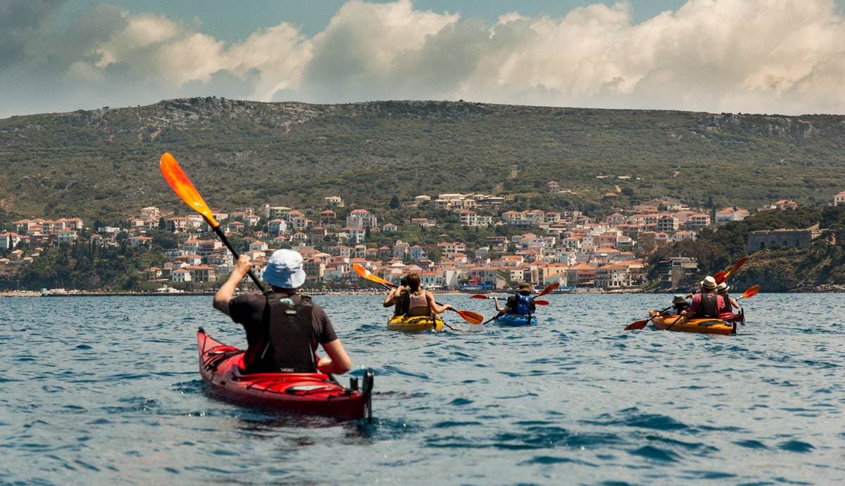 A group of kayakers paddling toward the scenic town of Pylos in the Peloponnese, Greece.