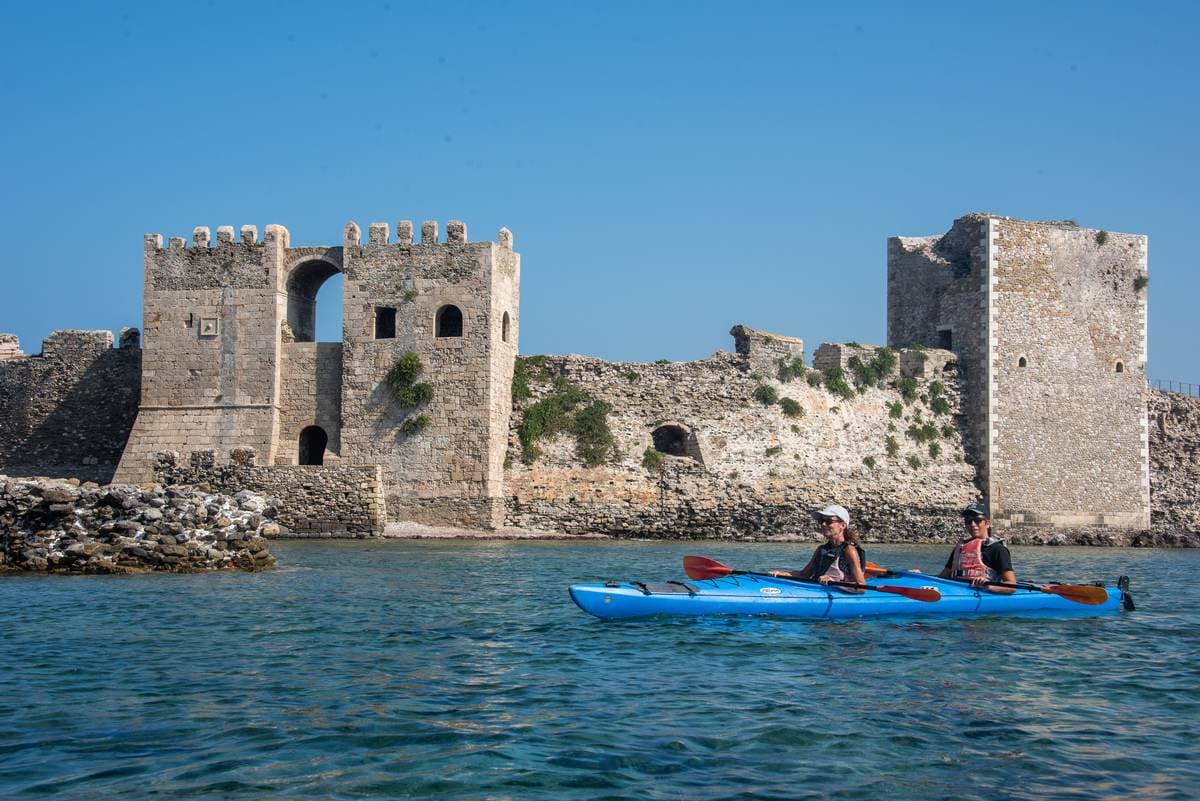 Sea kayakers paddling past the impressive medieval walls of Methoni Castle