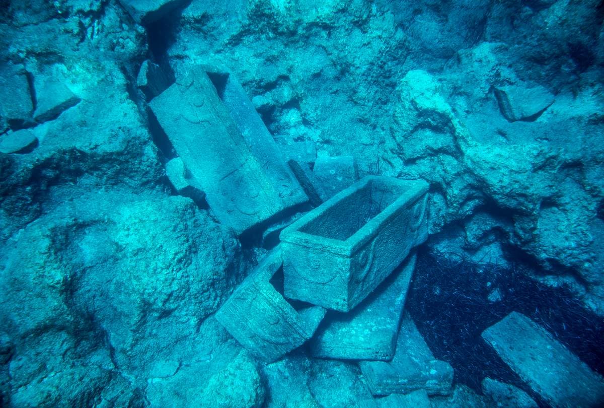 Underwater view of ancient stone sarcophagi visible on the seabed near the coast