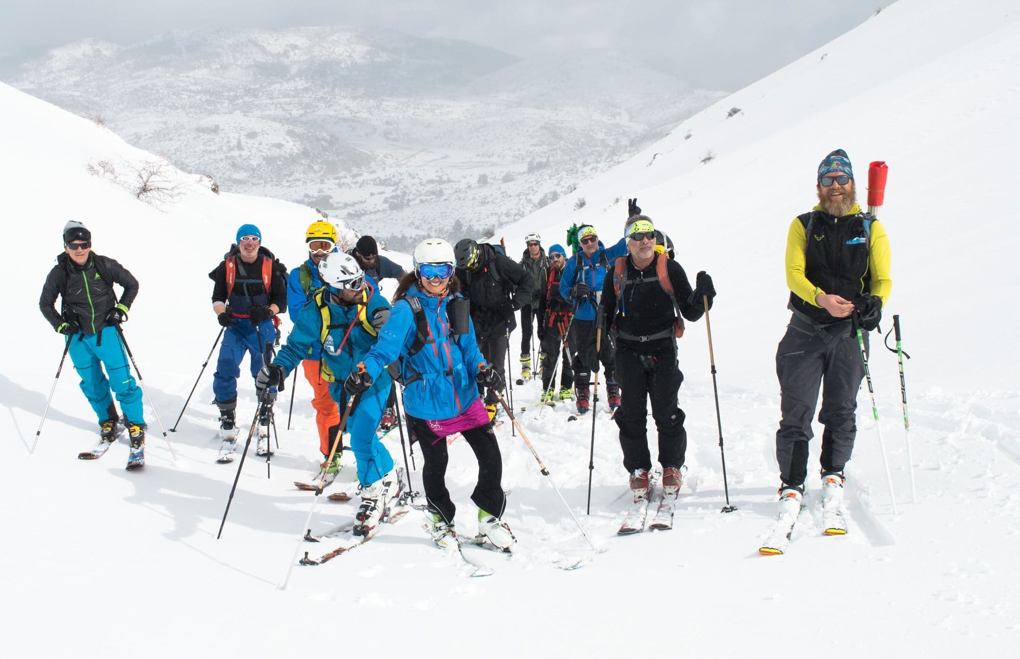 Group of ski tourers with poles and packs posing on a snowy mountain slope in Messinia
