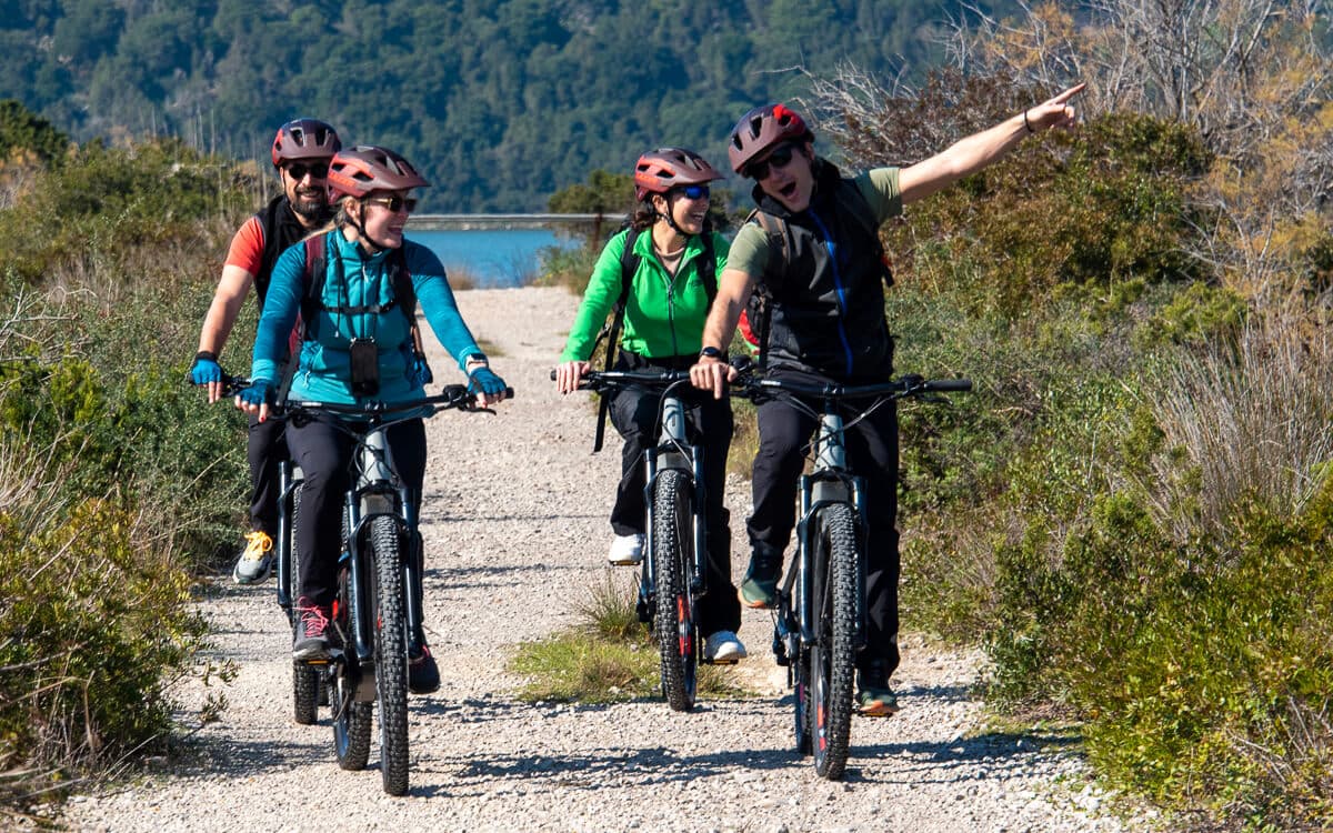 A happy group enjoying one of our guided cycling tours in Greece, riding on a scenic coastal gravel path.
