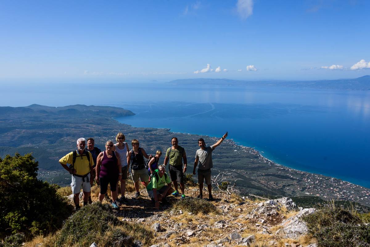 Guided hiking group standing on a ridge overlooking the city of Kalamata and the blue Messinian Gulf