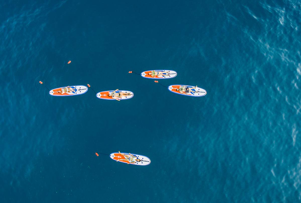 Alternative Text (Alt Text): Aerial view of guided SUP and snorkeling tour participants relaxing on paddleboards in the Messinian Gulf, Kalamata