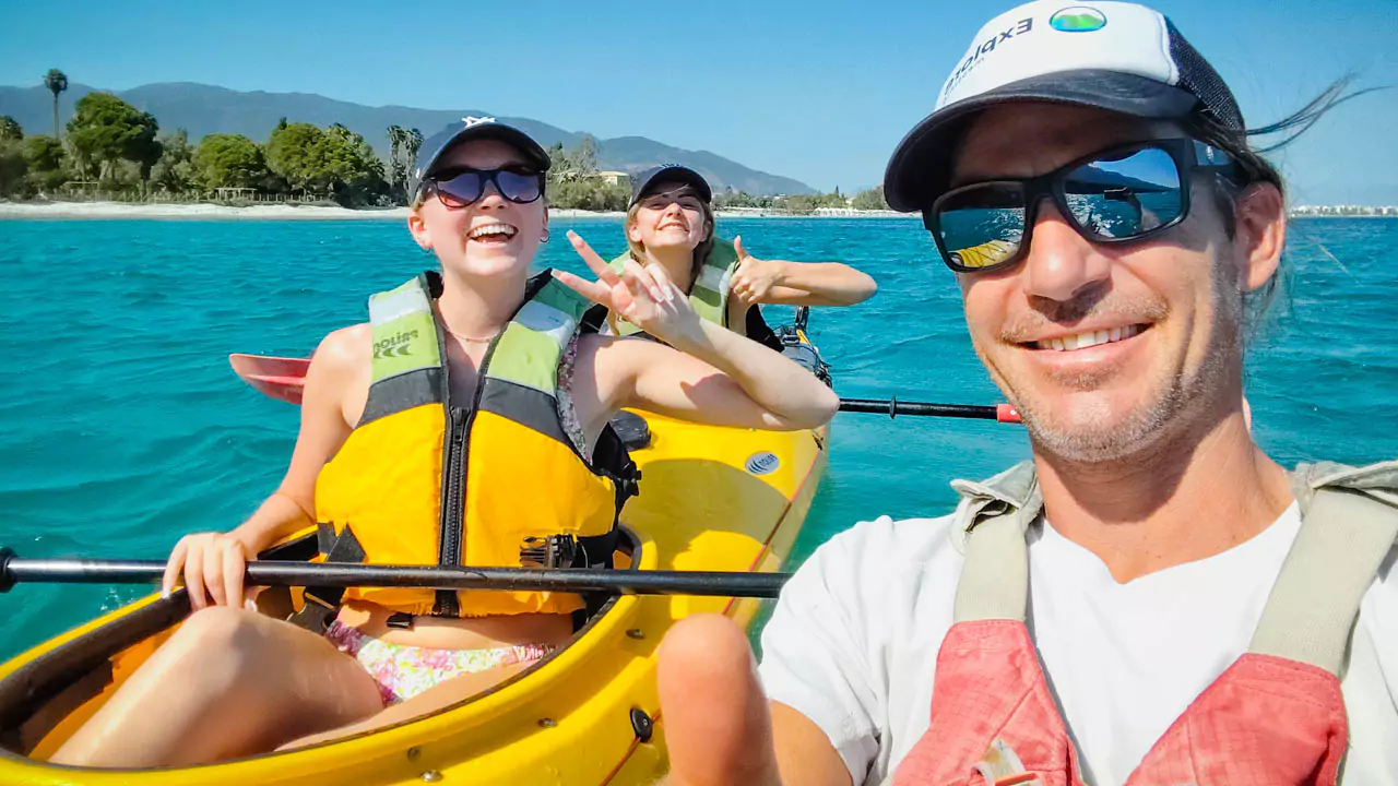 Explore MEssinia-Exploring peaceful bays in Kalamata Explore Messinia-Young teenagers with paddles, guided by an adult, exploring a peaceful bay in Messinia, Greece, emphasizing kid-friendly kayaking adventures.