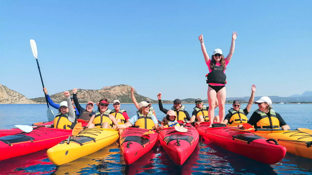 Explore Messinia-Paddling on calm turquoise waters, with scenic cliffs in the background. The joy of family kayaking. Explore Messinia-A smiling family in life jackets paddling together in a tandem kayak on calm turquoise waters, with scenic cliffs in the background, showcasing the joy of family kayaking.