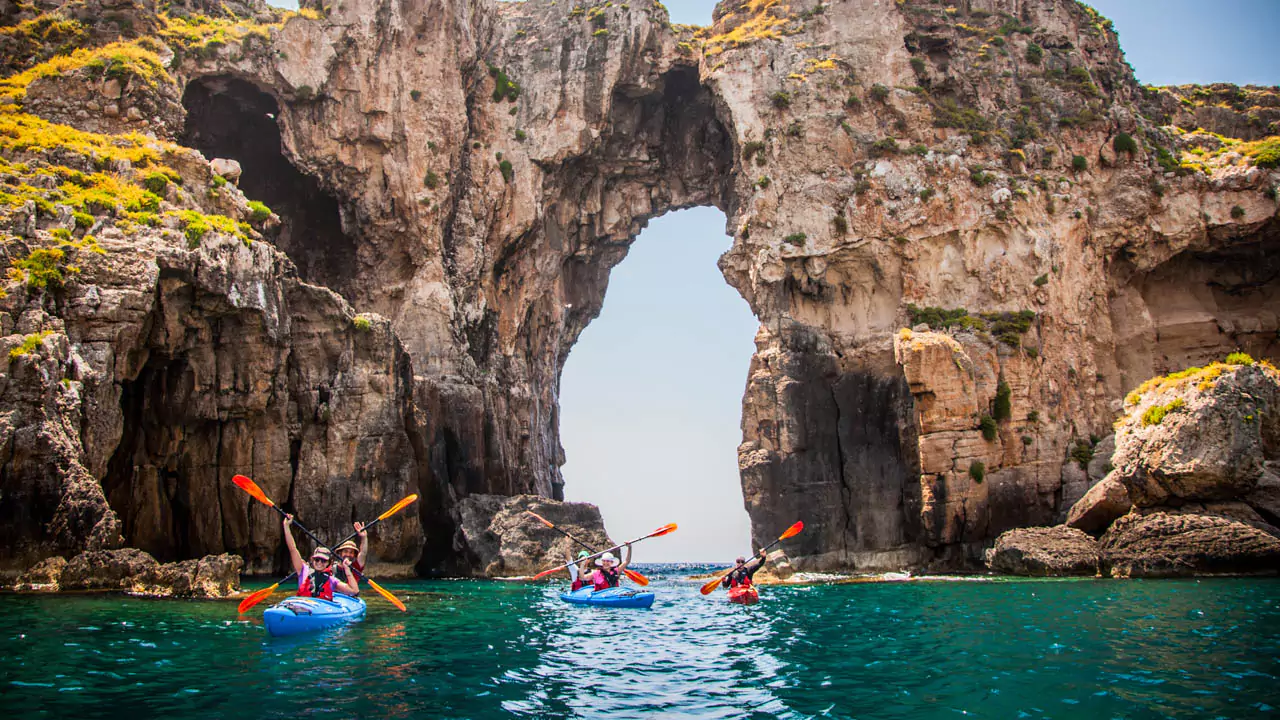 Explore Messinia-A group of kayakers glides through the emerald waters of Navarino Bay, dwarfed by the towering cliffs of majestic Sfaktiria Island. Explore Messinia-A group of kayakers glides through the emerald waters of Navarino Bay, dwarfed by the towering cliffs of majestic Sfaktiria Island.